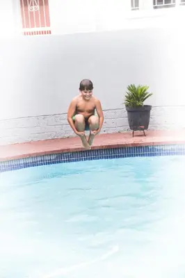 a man sitting on the edge of a swimming pool at 29 Polvy Street in Nelspruit