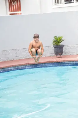 a man sitting on the side of a swimming pool at 29 Polvy Street in Nelspruit