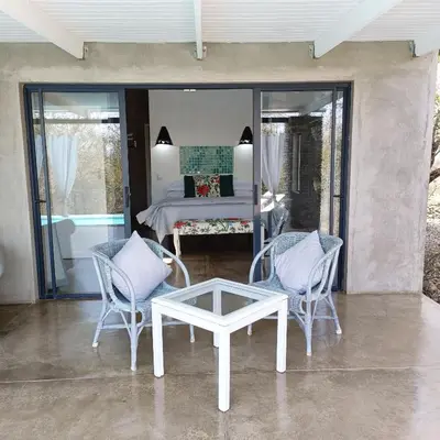 a patio with two chairs and a table and a bed at Kruger River Villas - LionsGate in Marloth Park