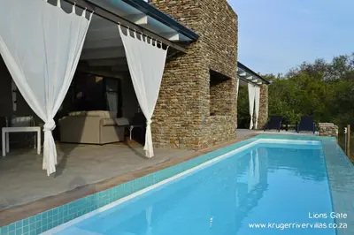 a swimming pool in front of a house at Kruger River Villas - LionsGate in Marloth Park