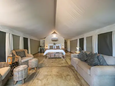 a large living room with a bed and a bedroom at Nyati Safari Lodge in Hoedspruit