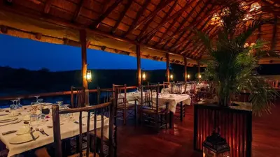 a restaurant with white tables and chairs with a view at Nyati Safari Lodge in Hoedspruit