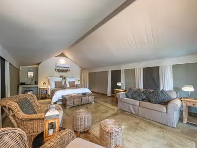 a bedroom with a bed and a living room at Nyati Safari Lodge in Hoedspruit