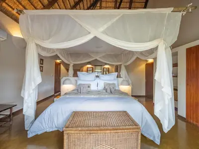 a bedroom with a large white bed with a canopy at Nyati Safari Lodge in Hoedspruit