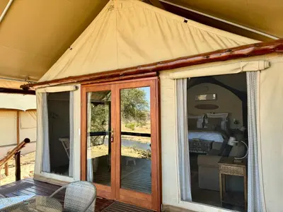 a tent with sliding glass doors and a bedroom at Nyati Safari Lodge in Hoedspruit