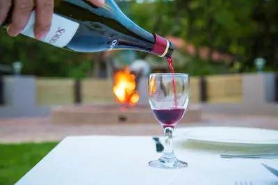 a person pouring a bottle of wine into a wine glass at Bush Lovers Lodge in Modimolle