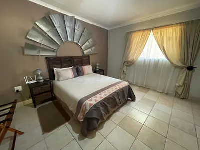 a bedroom with a large bed and a mirror at Bush Lovers Lodge in Modimolle