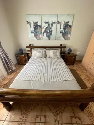 a bed in a room with four paintings on the wall at Bush Lovers Lodge in Modimolle