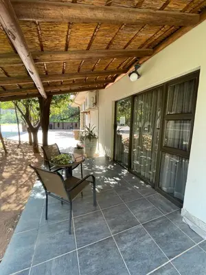 a patio with a table and chairs under a wooden ceiling at Bush Lovers Lodge in Modimolle