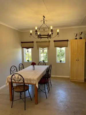 a dining room with a table with chairs and a chandelier at Rocks & Roses Farm stay in Lochiel