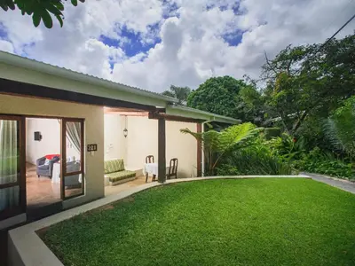 a garden with a lawn in front of a house at Stille Woning Guesthouse in White River