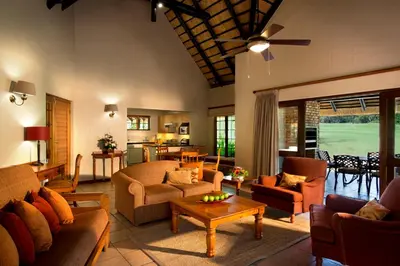 a living room with couches and a table at Kruger Park Lodge in Hazyview