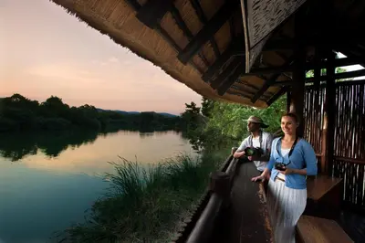 a man and a woman standing next to a river at Kruger Park Lodge in Hazyview