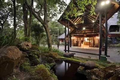 a building with a pool of water in front of it at Kruger Park Lodge in Hazyview