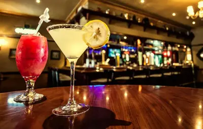 two cocktails sitting on a wooden table in a bar at Garden Court OR Tambo International Airport in Kempton Park