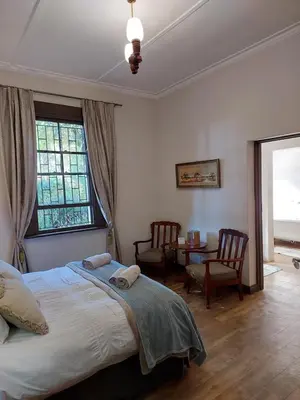 a bedroom with a bed and a table and a window at De Mist Graskop in Graskop