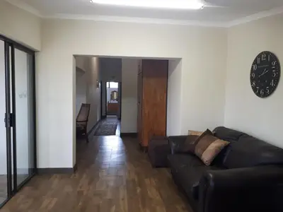 a living room with a couch and a clock on the wall at De Mist Graskop in Graskop