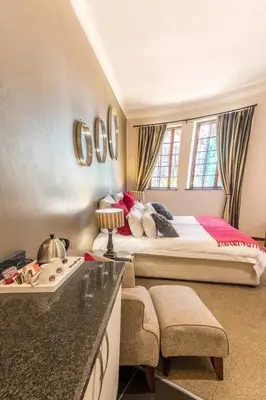 a bedroom with a king sized bed and a table at Constantia Hotel and Conference Centre in Midrand