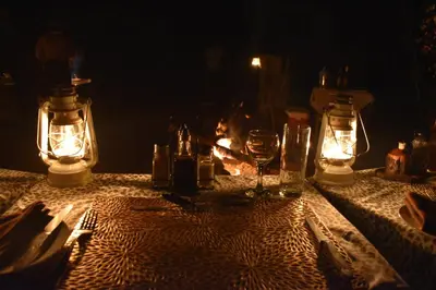 a table with candles and wine glasses and a fireplace at Masingitana Tented Camp in Hoedspruit