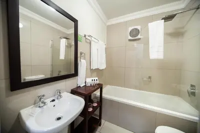 a bathroom with a sink and a tub and a mirror at Hotel @ Tzaneen in Tzaneen