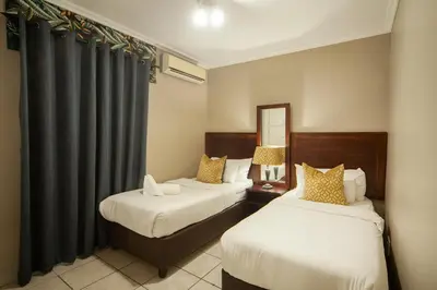 a hotel room with two beds and a mirror at Hotel @ Tzaneen in Tzaneen