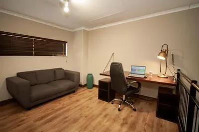 a living room with a couch and a desk with a computer at Hotel @ Tzaneen in Tzaneen