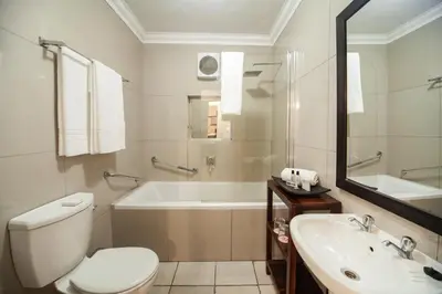 a bathroom with a toilet and a tub and a sink at Hotel @ Tzaneen in Tzaneen