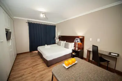 a hotel room with a bed and a table with oranges on it at Hotel @ Tzaneen in Tzaneen