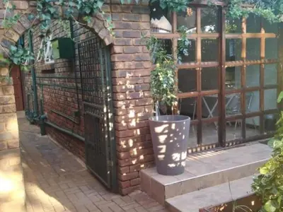 a brick wall with a gate and a potted plant at 8 Soenie Avenue Self-Catering in Pretoria