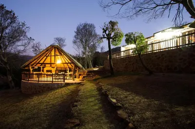 a large wooden cabin with a lit up roof at Rivendell Trout Estate in Lydenburg