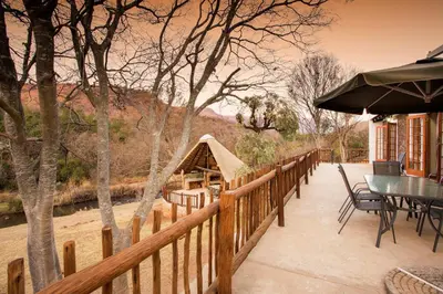 a wooden fence with a table and chairs on a patio at Rivendell Trout Estate in Lydenburg