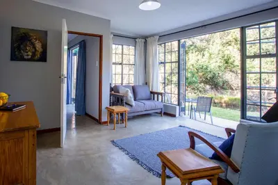 a living room with a couch and chairs and windows at Rivendell Trout Estate in Lydenburg