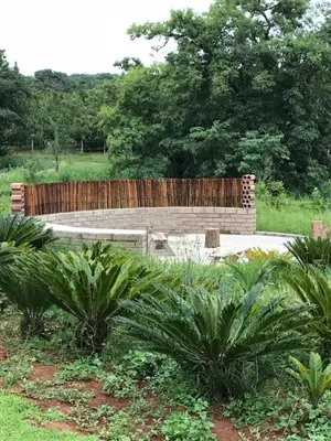 a wooden bench in a park with palm trees at Featherbrook Cottage in Tzaneen