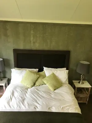 a bedroom with a bed with white sheets and pillows at Featherbrook Cottage in Tzaneen