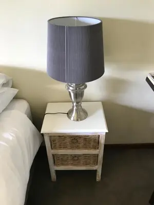 a lamp sitting on a table next to a bed at Featherbrook Cottage in Tzaneen