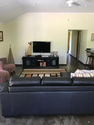 a living room with a couch and a flat screen tv at Featherbrook Cottage in Tzaneen