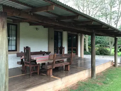 a patio with a table and benches on a house at Featherbrook Cottage in Tzaneen