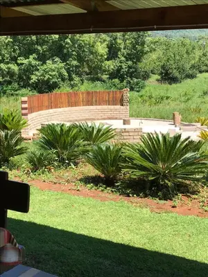 a wooden bench sitting in a garden with plants at Featherbrook Cottage in Tzaneen