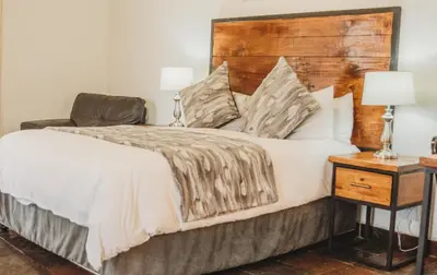 a bedroom with a large bed with a wooden headboard at Casa Leitao Lodge in Phalaborwa