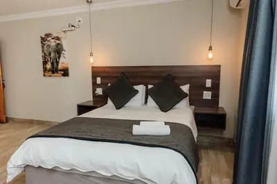 a bedroom with a large bed with a wooden headboard at Casa Leitao Lodge in Phalaborwa