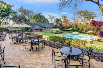 an outdoor patio with tables and chairs and a pool at Hazyview Sun in Hazyview