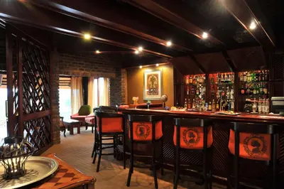 a bar in a restaurant with chairs and bottles of alcohol at Hazyview Sun in Hazyview