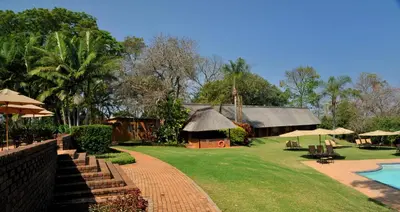 a resort with a pool and a building with a thatch roof at Hazyview Sun in Hazyview