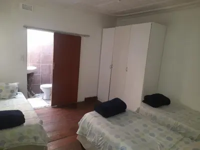a room with two beds and a bathroom with a toilet at 1322 Backpackers International in Pretoria