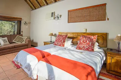 a bedroom with a large bed with red and white pillows at Boulders Safari Lodge in Malelane