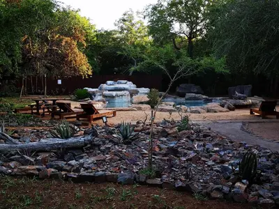 a garden with a fountain and picnic tables and benches at Boulders Safari Lodge in Malelane