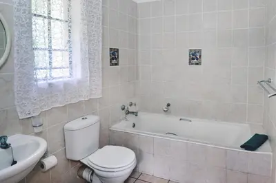 a bathroom with a toilet and a tub and a sink at Komati River Chalets in Komatipoort