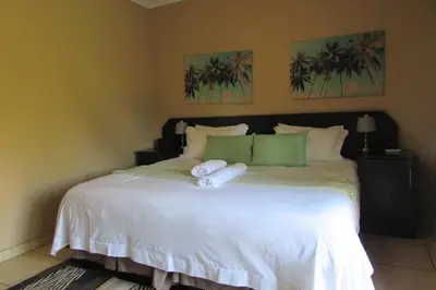 a bedroom with a large white bed with towels on it at Oasis Of Life Guest House in Witbank
