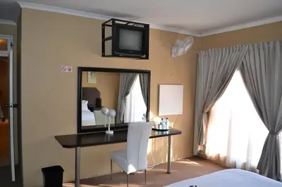 a bedroom with a desk with a mirror and a tv on the wall at Oasis Of Life Guest House in Witbank