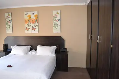 a bedroom with a bed with white sheets and pillows at Oasis Of Life Guest House in Witbank